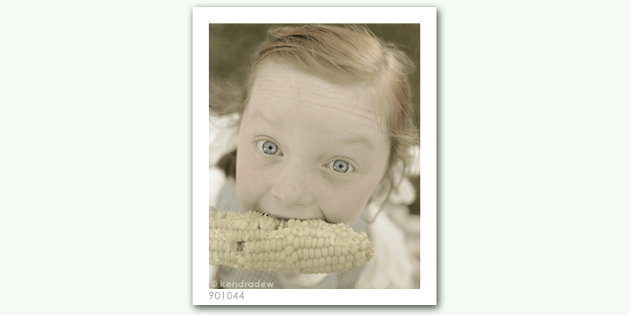 photograph of girl eating corn