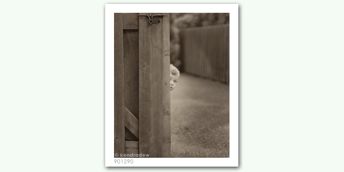 photograph of boy peeking around corner