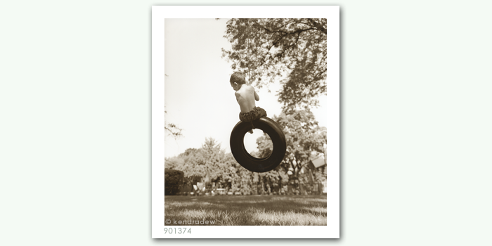 photograph of boy on tire swing