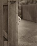 photograph of boy peeking around corner